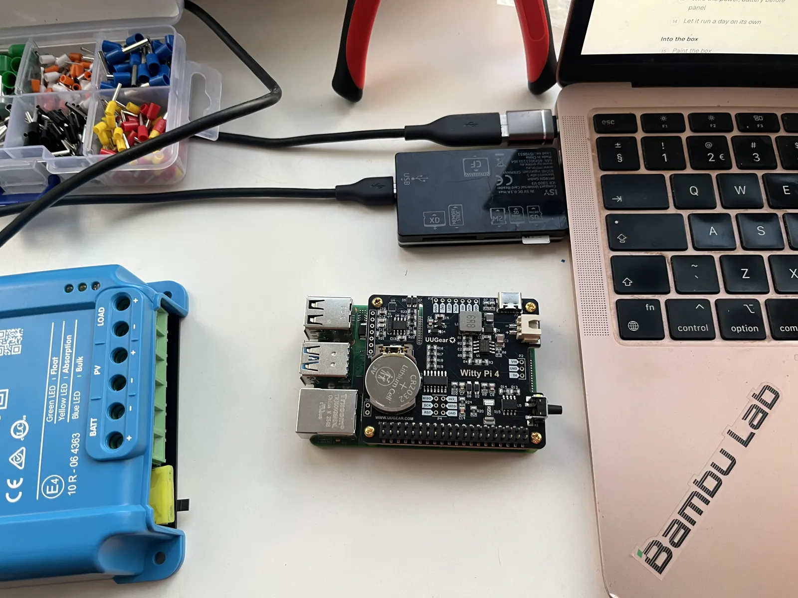 The memory card in a card reader plugged into the laptop, the Raspberry Pi with the Witty Pi waiting beside it