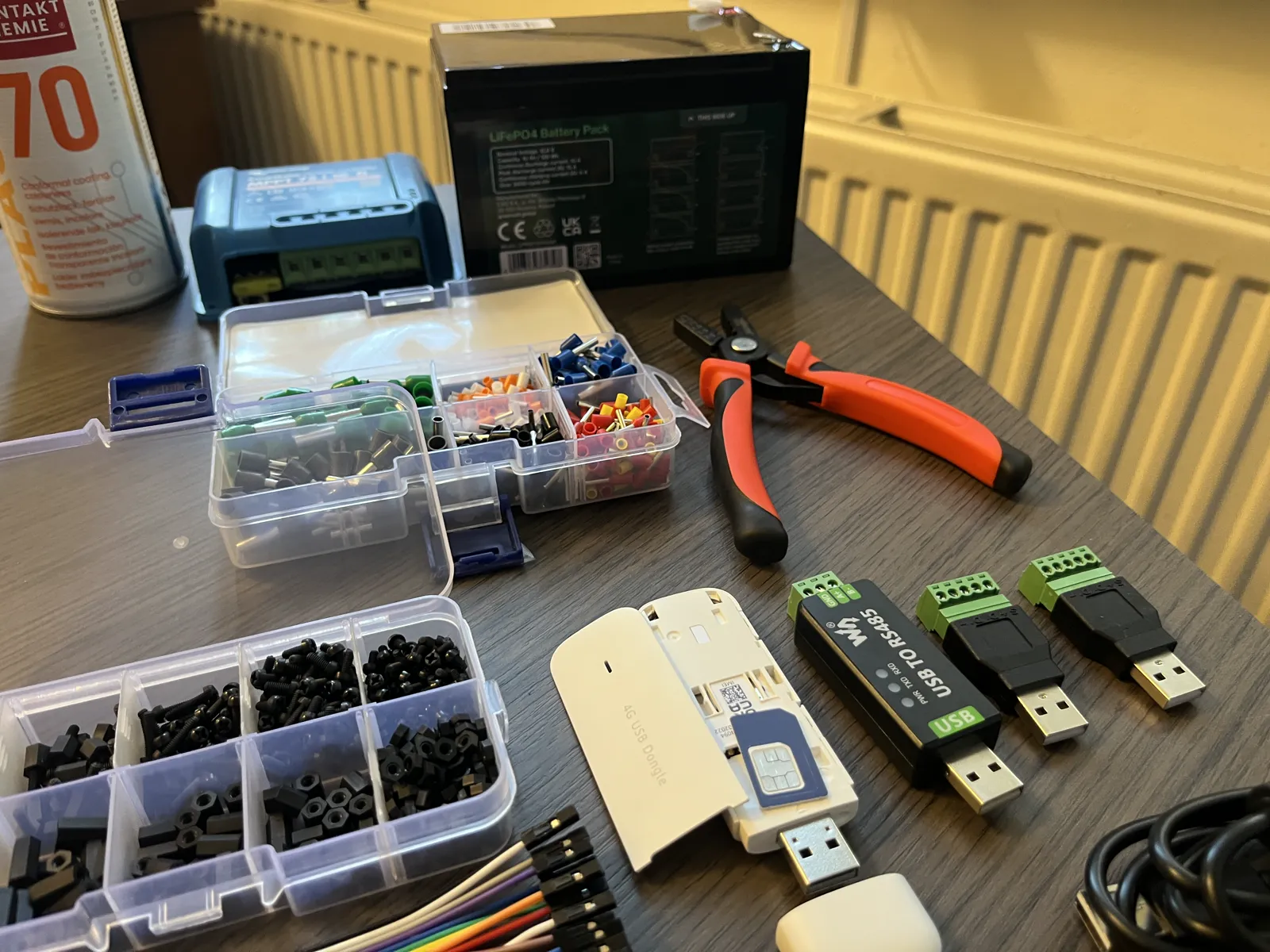 The white 4G stick opened with the SIM card in its slot, next to the RS485 adapter, two USB screw terminals, the crimping pliers and the box of ferrules